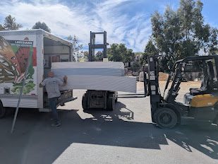 Drywall being unloaded from a delivery truck by forklift